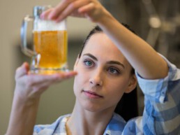 Junge Frau hält ein Glas Bier in der Hand und prüft die Qualität