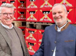 Reinhard Holz und Harald Schmidt stehen vor roten Fürst Wallerstein Bierkästen