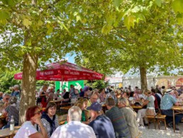 Menschen sitzen unter Bäumen im Sixengarten