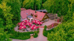 Luftaufnahme Biergarten im Wald mit roten Schirmen