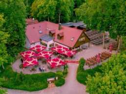 Luftaufnahme Biergarten im Wald mit roten Schirmen