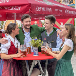 Gruppe junger Menschen in Tracht stehen um einen Tisch