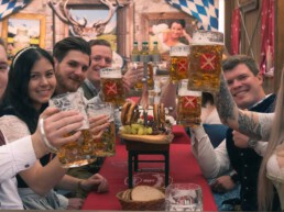 Junge Menschen sitzen im Bierzelt und prosten