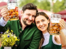 ein mann und eine frau posten mit maßkrügen in die kamera