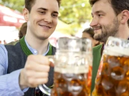 zwei junge männer prosten mit maßkrügen im sixengarten