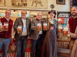 Vertreter der Stadt Wassertrüdingen, der Festwirtfamilie Papert und des Fürst Wallerstein Brauhauses stoßen bei der Bierprobe zum Volksfest 2026 im Weißen Ross mit frisch gezapften Maßkrügen auf das neue Festbier an.