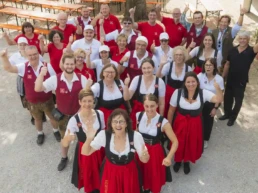 Gruppenfoto des Sixengarten-Teams und von Cook's Partyservice auf der Nördlinger Mess' 2026. Mitarbeiterinnen und Mitarbeiter in Dirndl, Servicekleidung und Brauhaus-Westen stehen auf dem Festgelände zusammen und zeigen gut gelaunt den Daumen nach oben. Carl-Eugen Prinz zu Oettingen-Wallerstein ist ebenfalls auf dem Bild zu sehen.